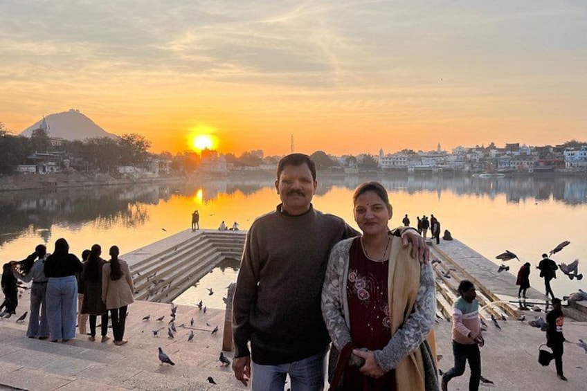 A sunset over a body of water with people and birds around. 3