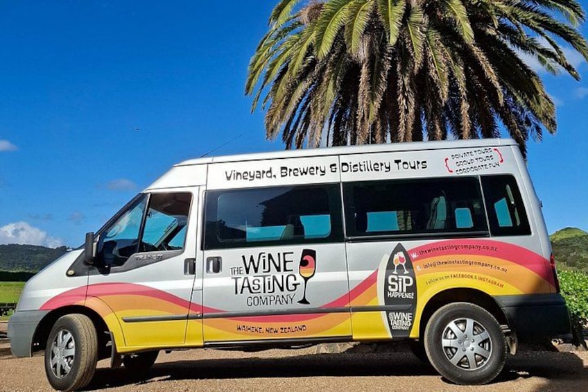 Una camioneta blanca con gráficos y texto llamativos que anuncia tours a viñedos, cervecerías y destilerías. 2
