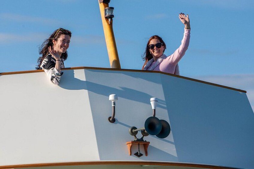 Two people on a boat, one waving. 4