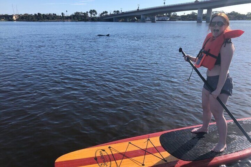 A person paddleboarding on a river with a bridge in the background. 4