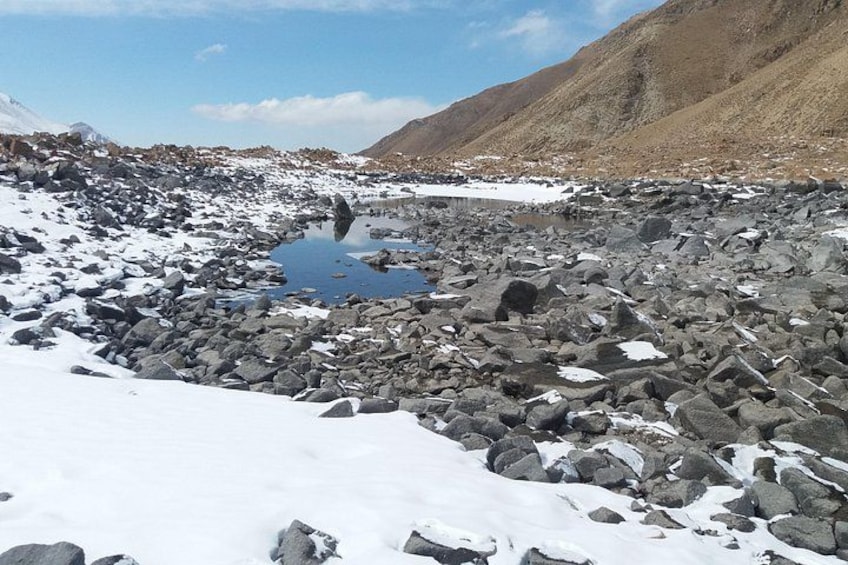 Un paisaje montañoso cubierto de nieve con un arroyo pedregoso. 4
