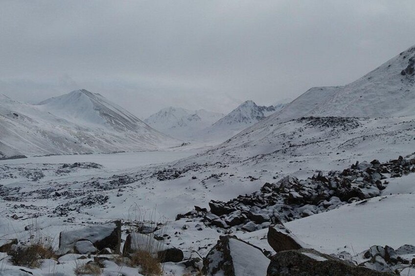 Un paisaje montañoso nevado con terreno rocoso y cumbres distantes. 5