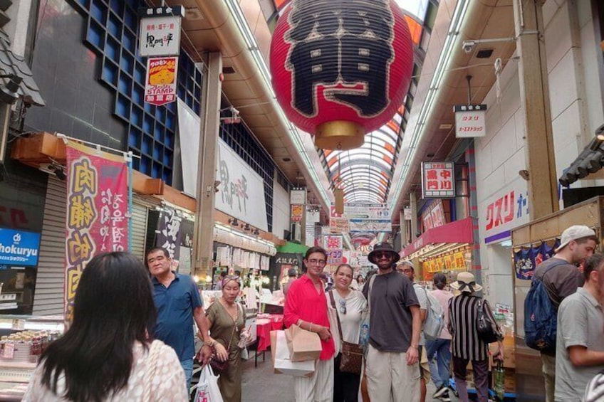 A busy indoor market with various stalls and hanging signs. 2
