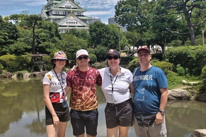 Four people standing by a pond with a castle in the background. 5