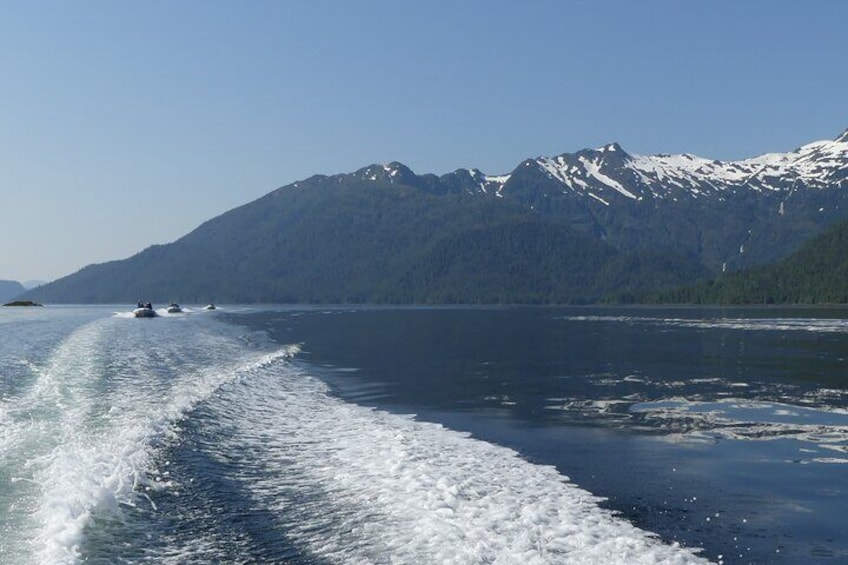 A boat moving through a calm lake with snow-capped mountains in the background. 5