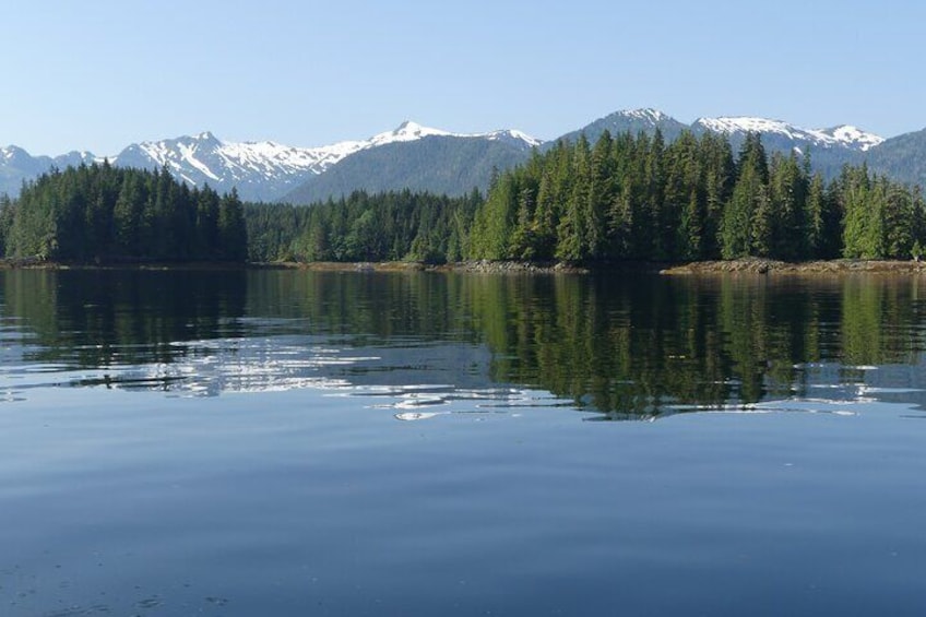 A calm lake with reflections of trees and snow-capped mountains in the background. 4