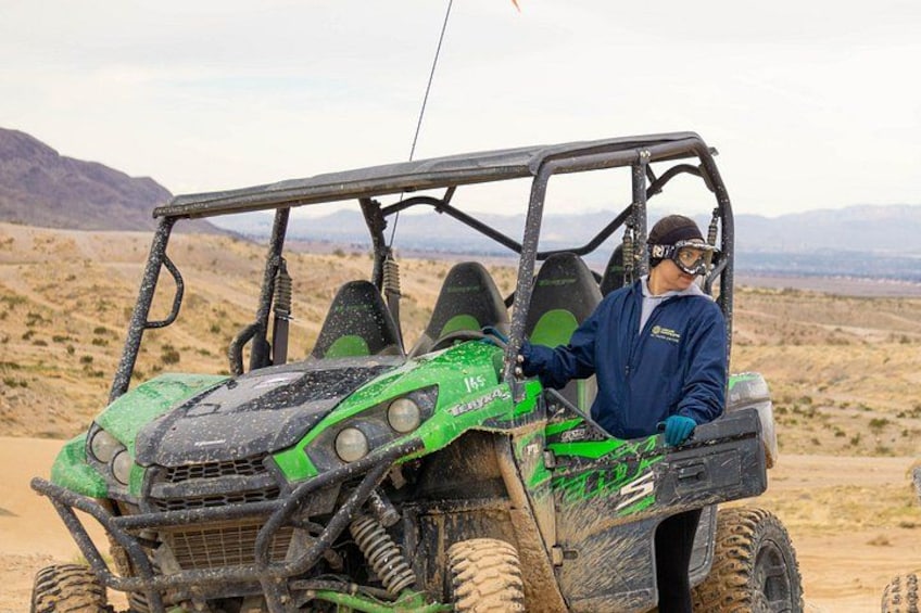A person driving a green off-road vehicle in a desert landscape. 5