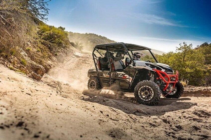 A vehicle driving on a dirt road surrounded by sparse vegetation. 4