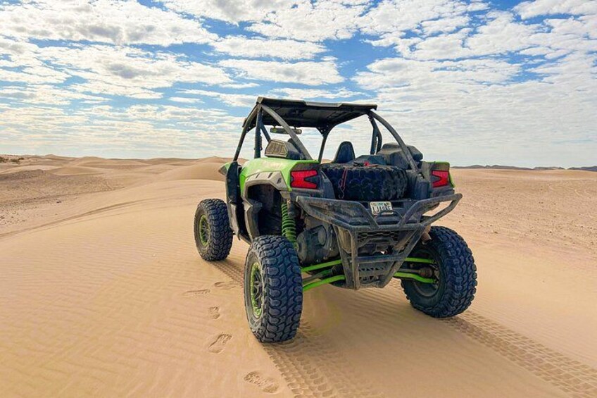 A green off-road vehicle on a sandy desert path. 3