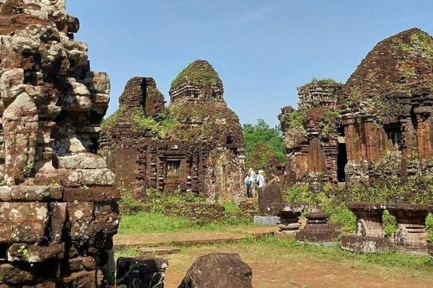Ancient ruins with multiple structures, including a prominent temple with a conical roof, surrounded by overgrown vegetation. 4