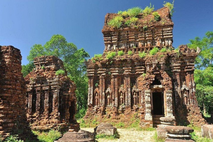 Ancient brick ruins with columns and statues, surrounded by greenery. 3