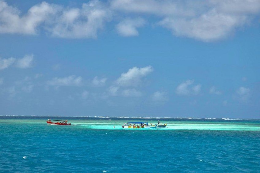 A turquoise sea with two boats, one red and one blue, under a clear sky. 3