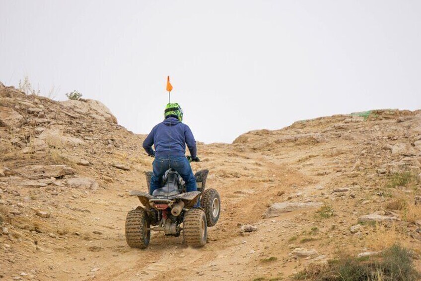 A person riding a quad bike on a dirt trail. 1