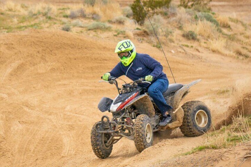 A person riding a quad bike on a dirt trail. 5