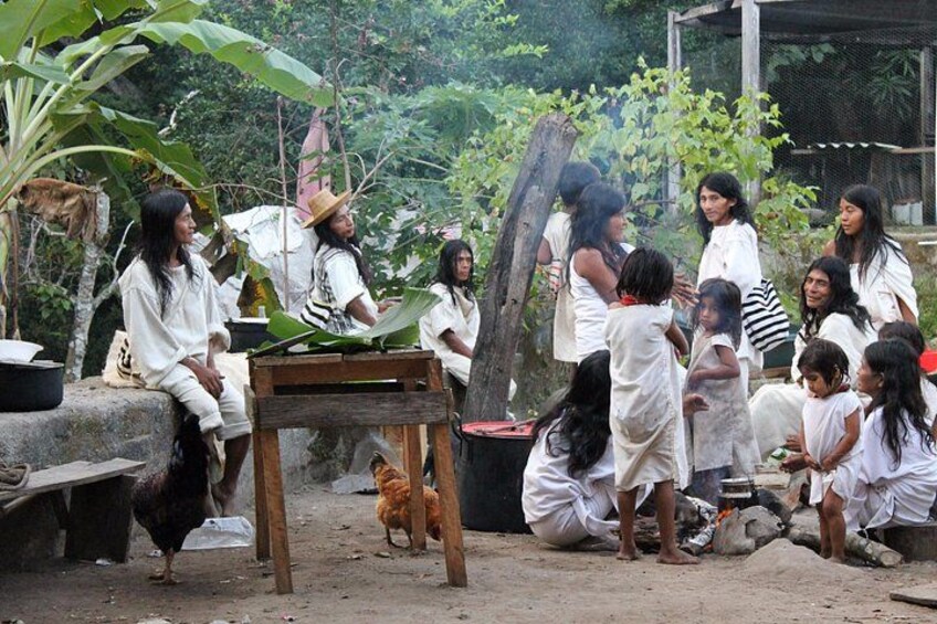 A group of people in a rural outdoor setting with a chicken, a wooden table, and a black container. 5