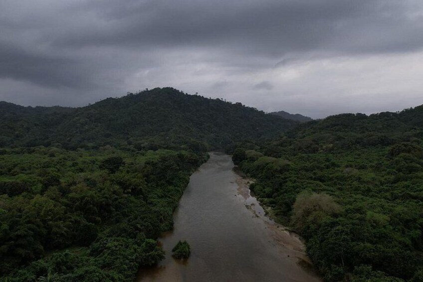 A river winding through a dense, green forested landscape with hills in the background. 4