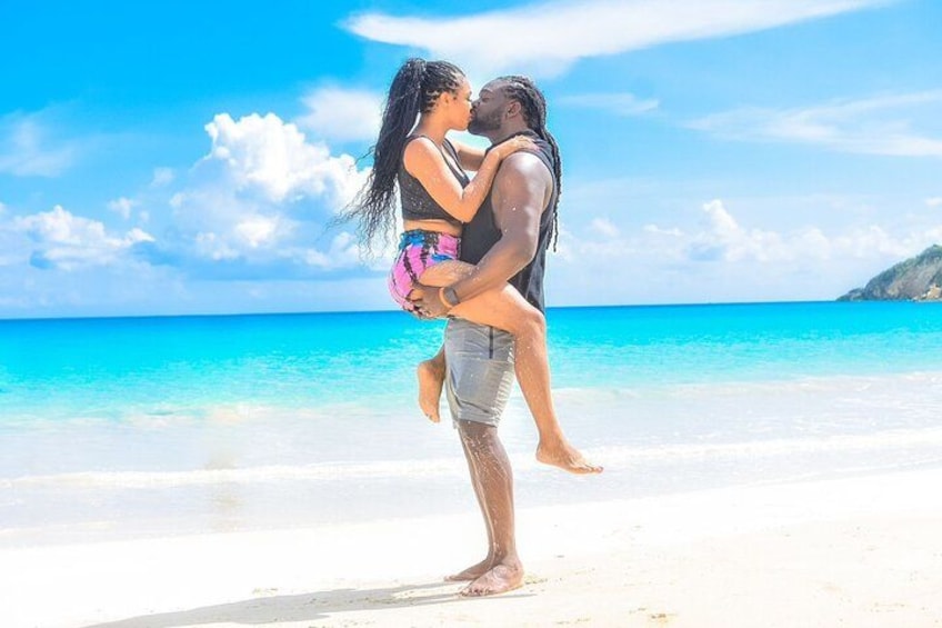 Una pareja en la playa con aguas azules cristalinas y una montaña distante. 4