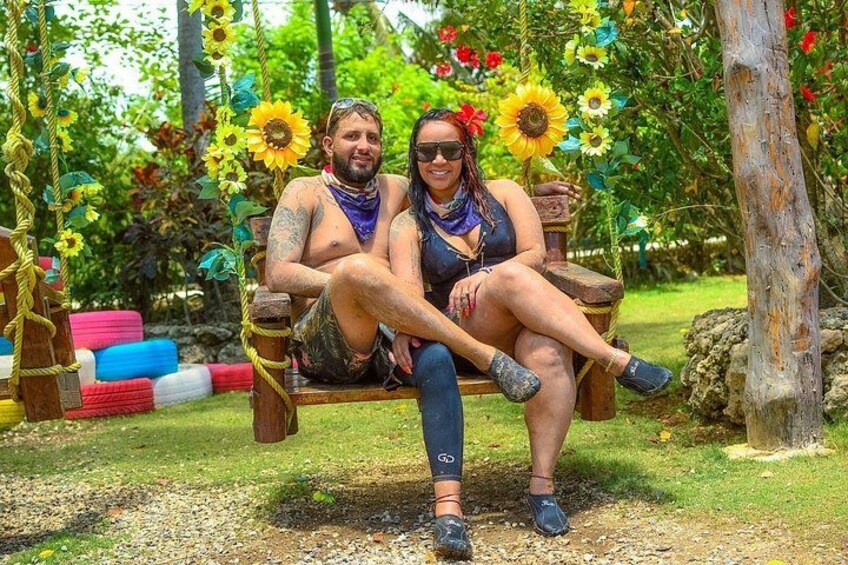 Two people sitting on a swing in a garden with sunflowers and colorful flowers. 3