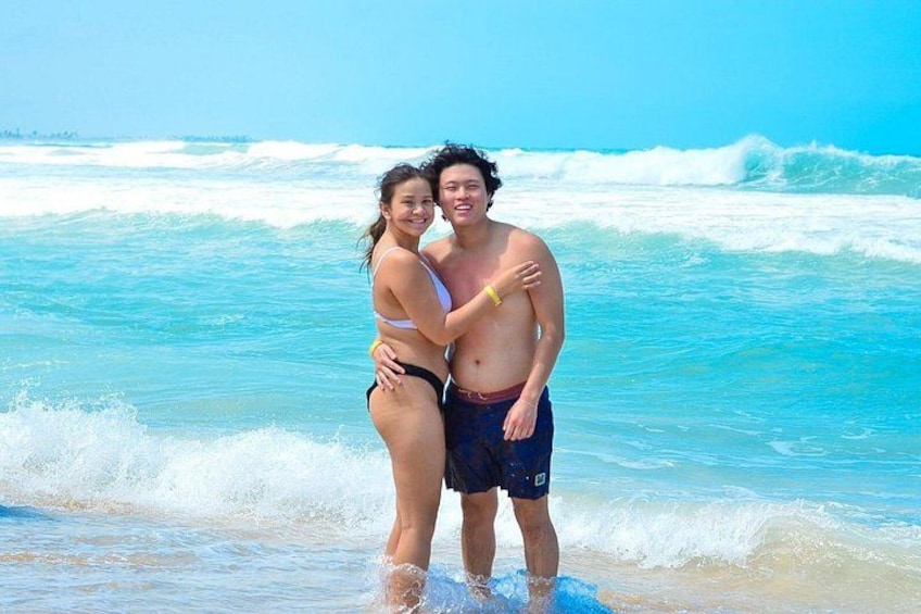 A couple embracing on a beach with waves in the background. 3