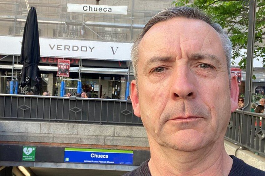 A man in front of a building with a sign that reads 'Chueca.' 2