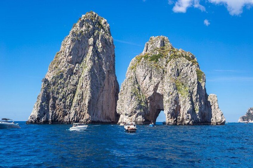 Two large rock formations with a clear blue sky and calm sea. 4