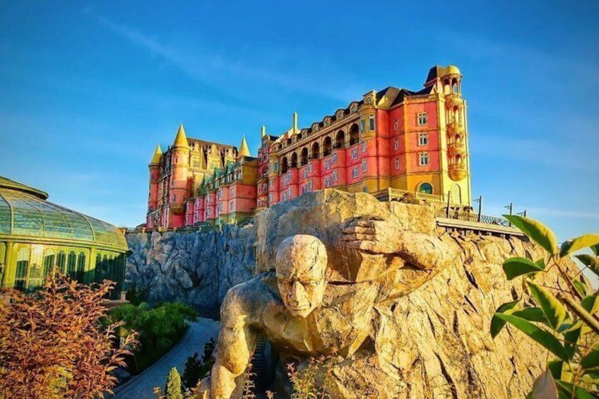 A castle on a rocky cliff, a large statue, and a glass greenhouse. 3