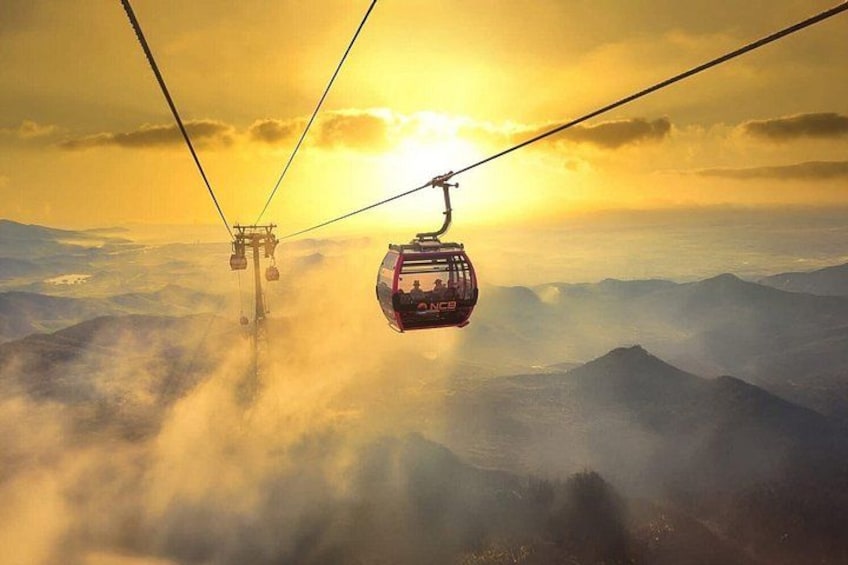 Eine Seilbahn über einer gebirgigen Landschaft, im Hintergrund ein Sonnenaufgang. 4
