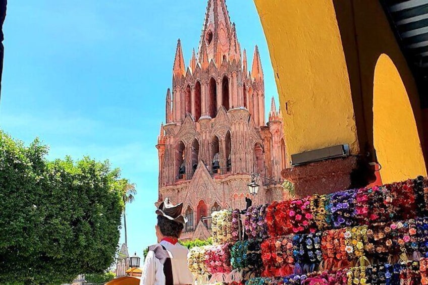 Une cathédrale gothique aux flèches complexes, avec un parterre de fleurs aux couleurs vives en premier plan. 1