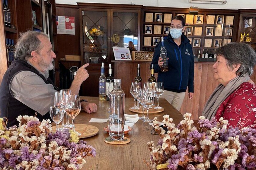 A wine tasting event with a wooden table, wine bottles, glasses, and a person holding a bottle. 4