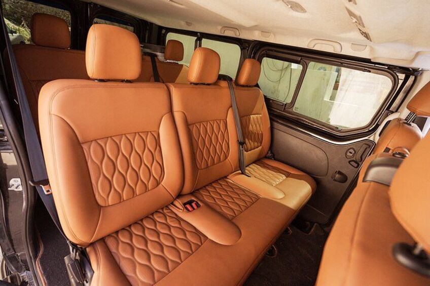 A vehicle interior with tan leather seats and a center console. 2