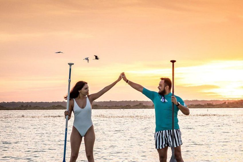 Dos personas haciendo paddleboard en un cuerpo de agua durante el atardecer. 2