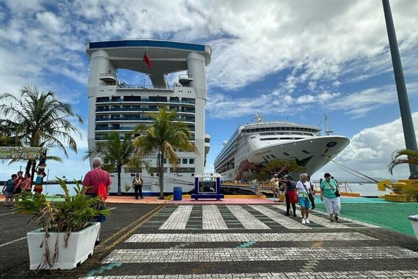 A cruise ship docked at a port with a large building in the background. 3