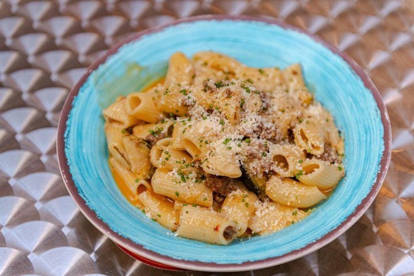 A bowl of pasta with a creamy sauce, garnished with herbs and grated cheese. 5
