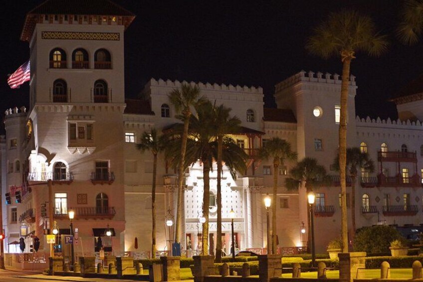 Un edificio histórico con una torre, palmeras y una calle bien iluminada. 3