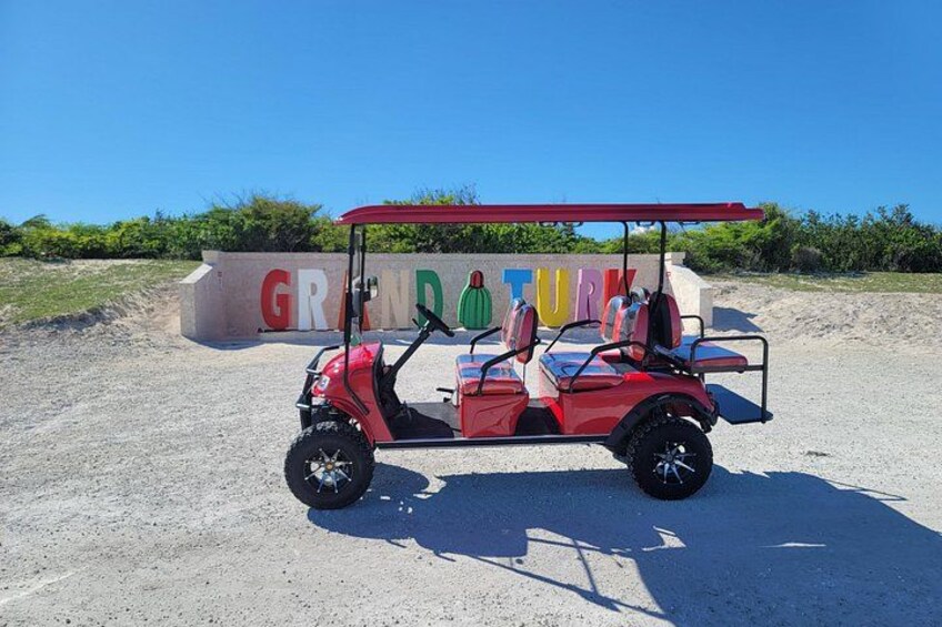 A red golf cart parked in front of a sign that reads 'GRAND TURF.' 5