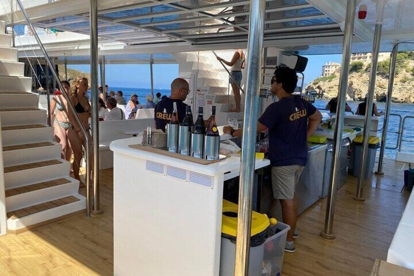 A boat deck with a bar area, a staircase, and people. 3