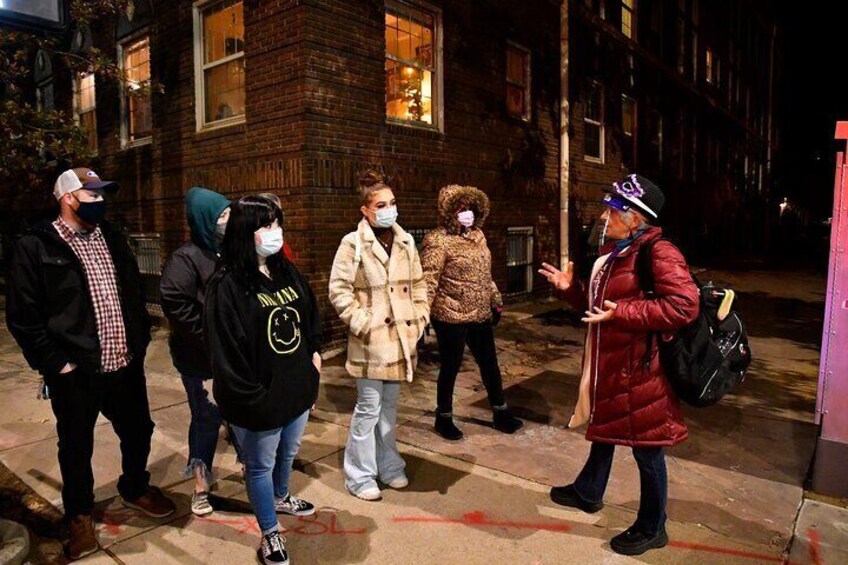 A group of people standing on a sidewalk at night. 3