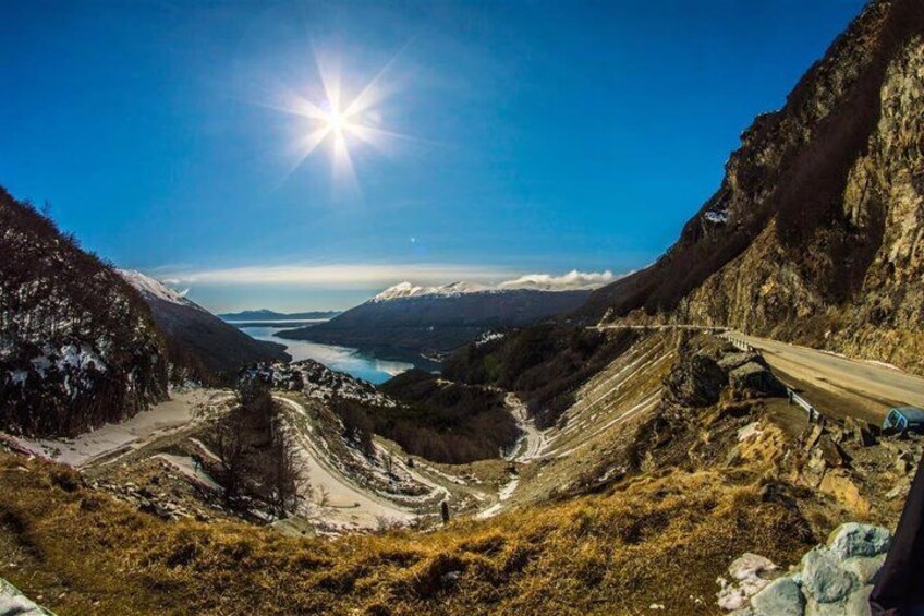 Un paysage montagneux avec une route sinueuse, une vallée et une étendue d’eau. 1