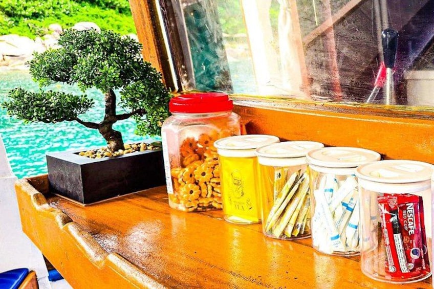 A wooden table with a bonsai tree, jars of snacks, and a red can. 3