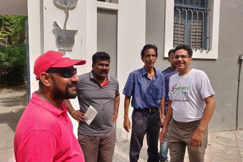 Four men standing in front of a building with a window and a door. 2