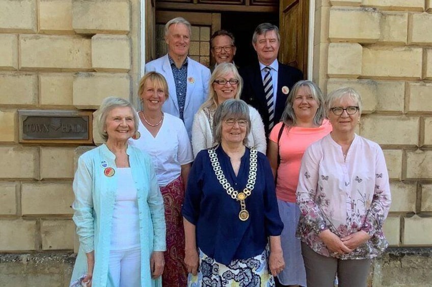 A group of people standing in front of a building with a plaque that reads 'TOWN HALL'. 2