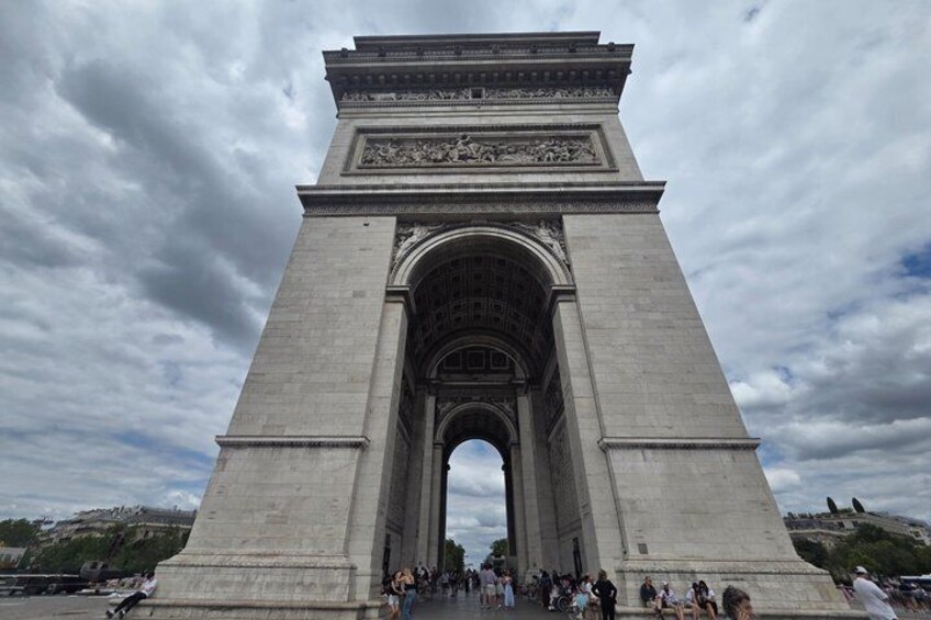 A large stone archway with intricate carvings at the top, surrounded by a crowd of people. 4