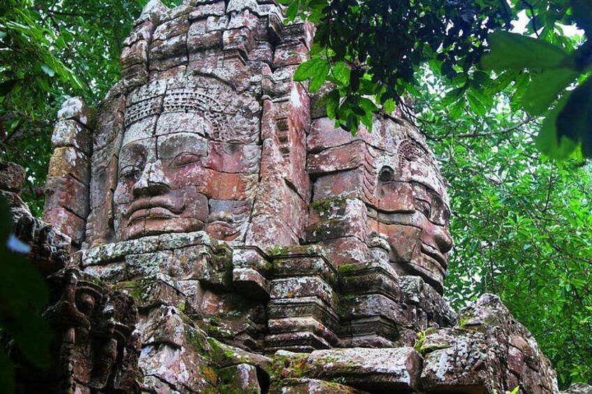A weathered stone structure with intricate carvings, surrounded by lush greenery. 5