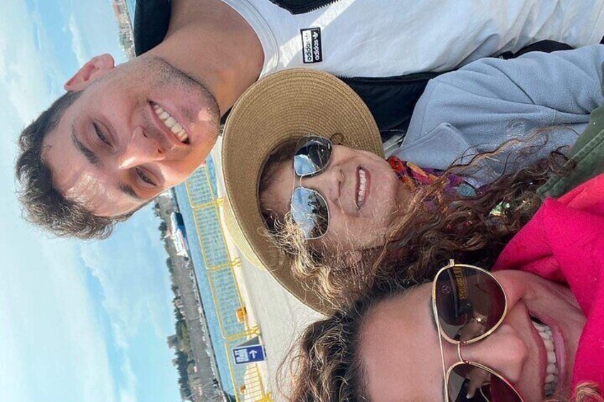 A person wearing a straw hat and sunglasses, with a blue sky and a distant view of a coastal area. 1