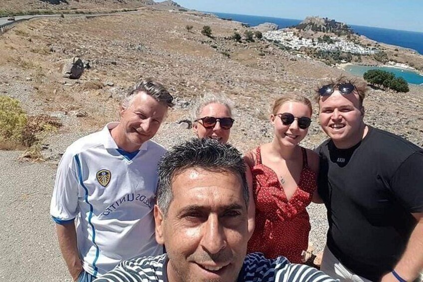 A group of people on a coastal road with a view of a rocky landscape and the sea. 2
