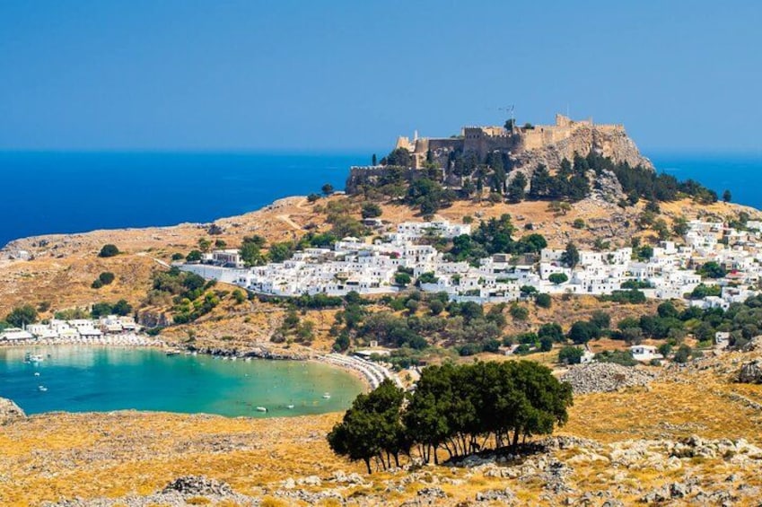 A coastal town with a castle on a hill, white buildings, and a clear blue sea. 1