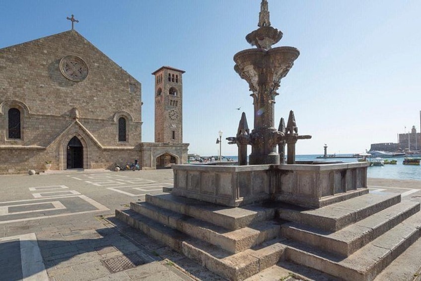 Una iglesia con una torre de campanario, una fuente y un muelle al fondo. 4