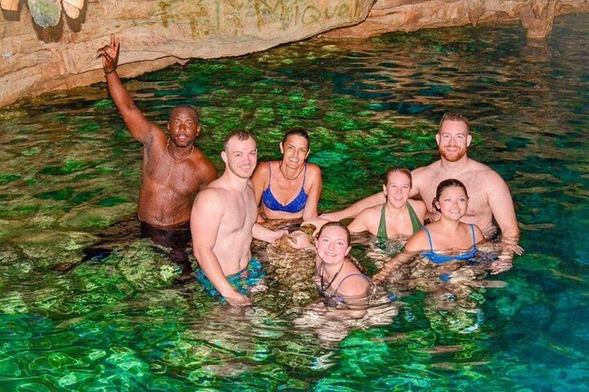 Un grupo de personas en una piscina natural con agua cristalina, rodeado de formaciones rocosas. 5