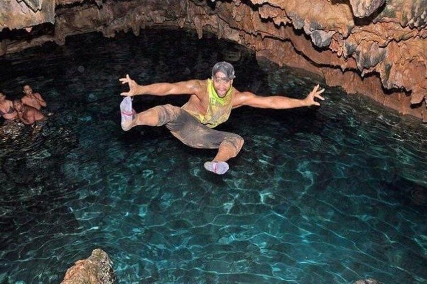 A person floating in a clear pool with rocky cave walls. 4