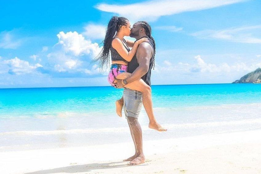 Una pareja se abraza en una playa con aguas turquesas cristalinas y una isla distante. 4